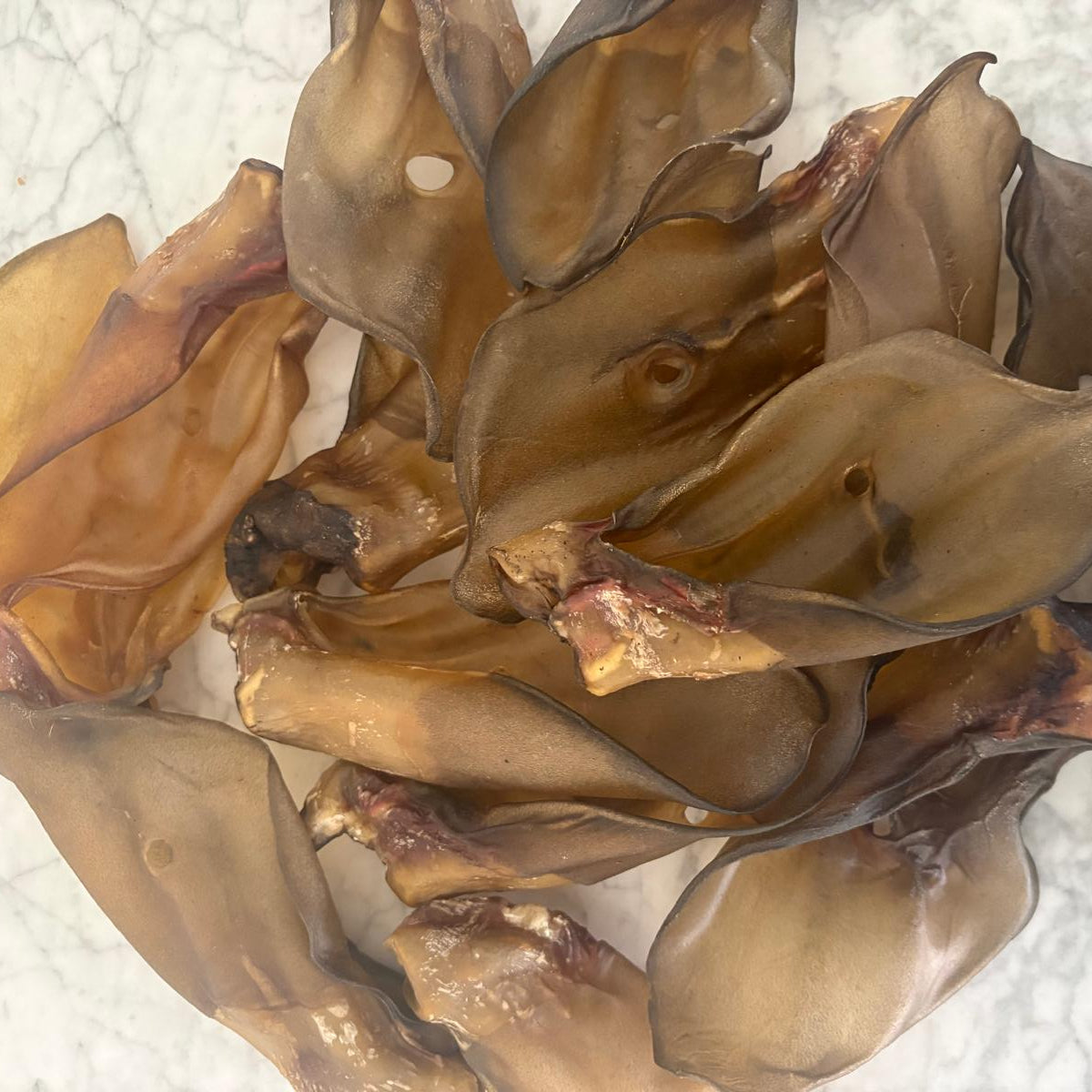 Stack of natural Dried Beef Ears on a marble surface