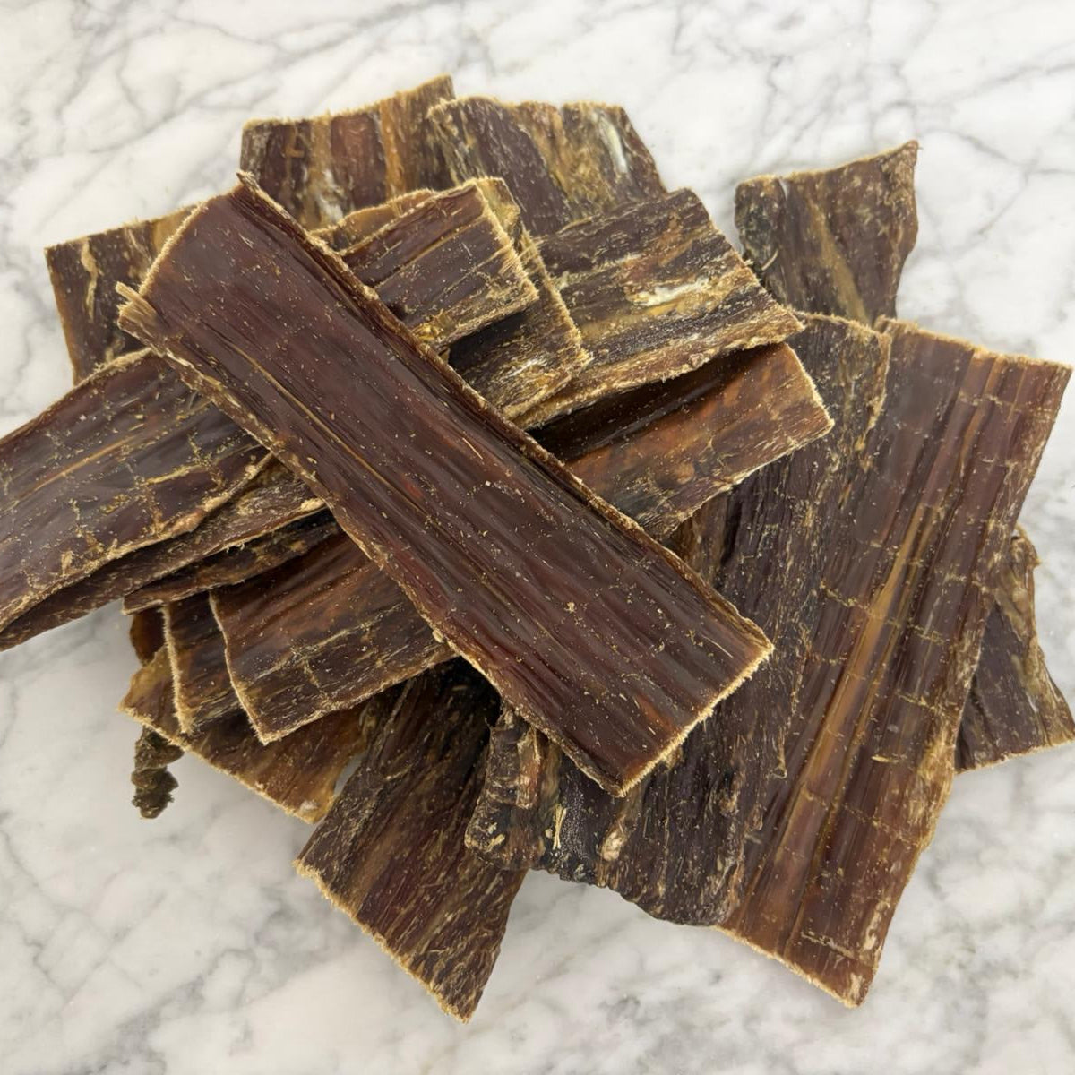 Stack of natural flat beef dog treats on a marble top