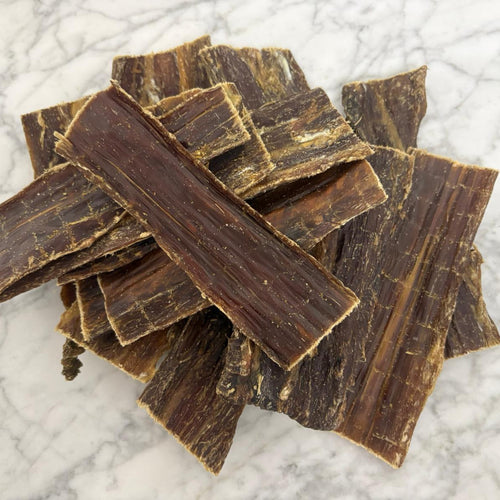 Stack of natural flat beef dog treats on a marble top