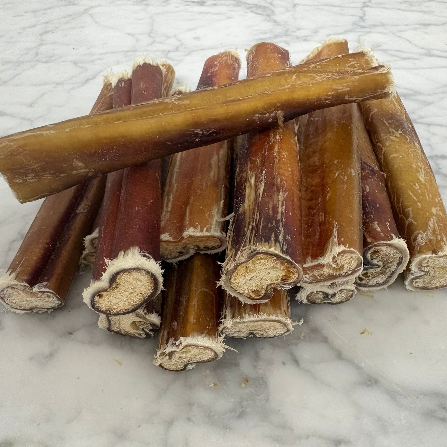 Natural dog chew pizzle sticks on a marble surface